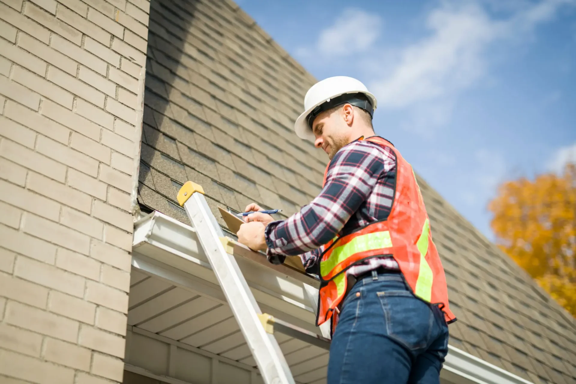 Roofer in safety gear on ladder